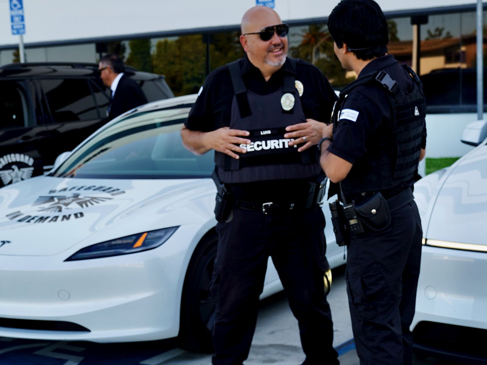 Licensed armed security guard company officers reviewing post orders in front of Safeguard On Demand marked vehicles in Santa Ana, CA