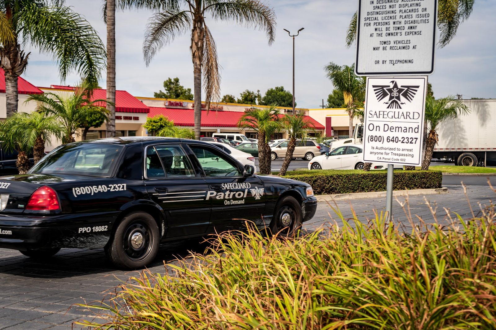 Safeguard On Demand marked patrol vehicle at a shopping center with posted security signage